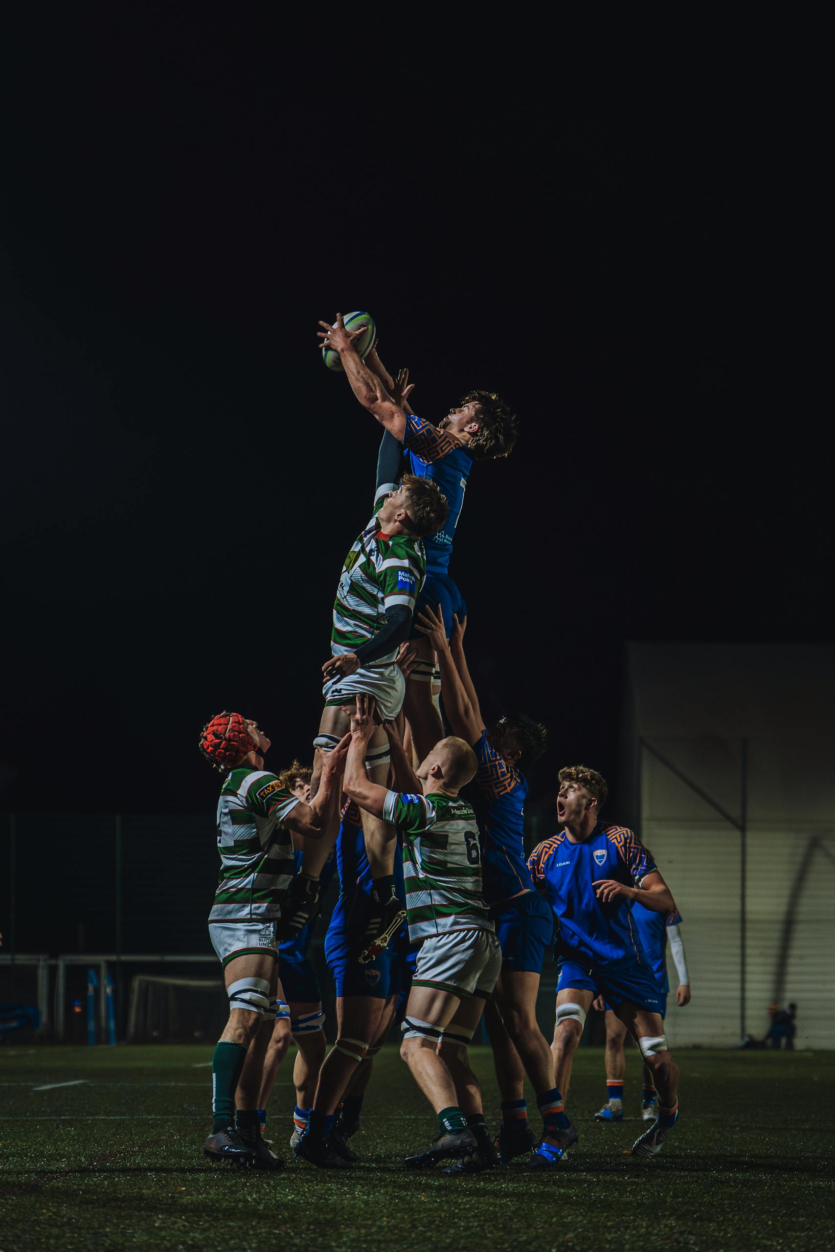 Exciting night-time rugby match showcasing a line-out in England.